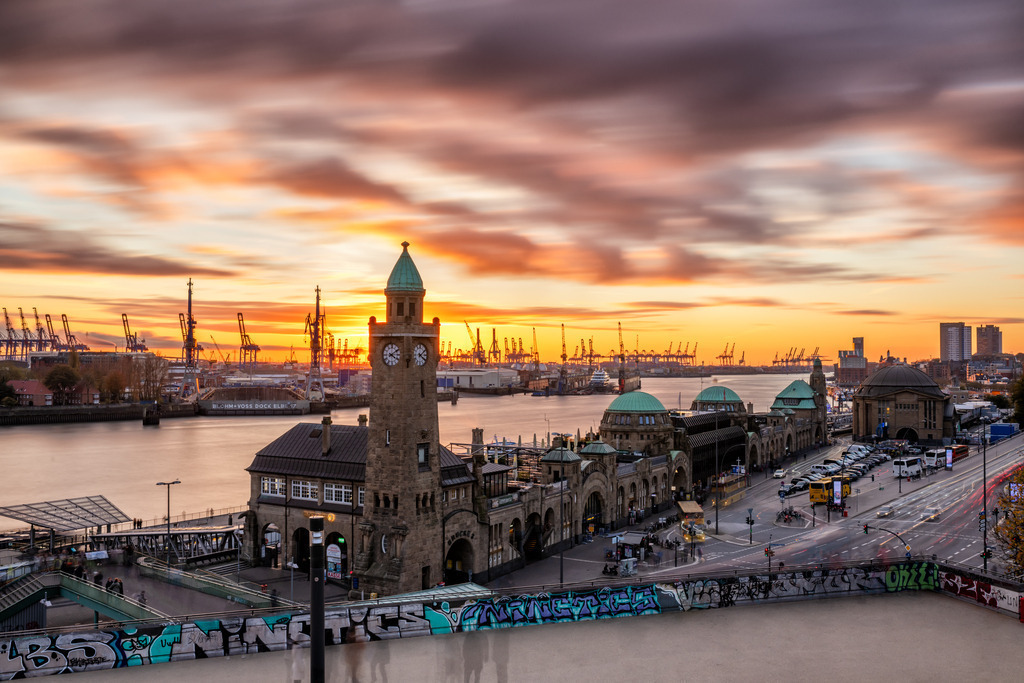 10240207 - Traumhafter Ausblick | Blick auf die Landungsbrücken und den Hamburger Hafen bei Sonnenuntergang, aufgenommen mit einer Langzeitbelichtung durch die die Menschen im Vordergrund nur schemenhaft zu sehen sind.