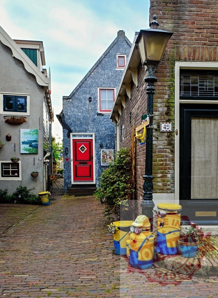 Minion-styled trash cans decorating a picturesque alley in the Netherlands | Three minion-styled trash cans standing in a picturesque alley in the Netherlands, adding a touch of whimsy to the traditional brick paved street - Realized with Pictrs.com