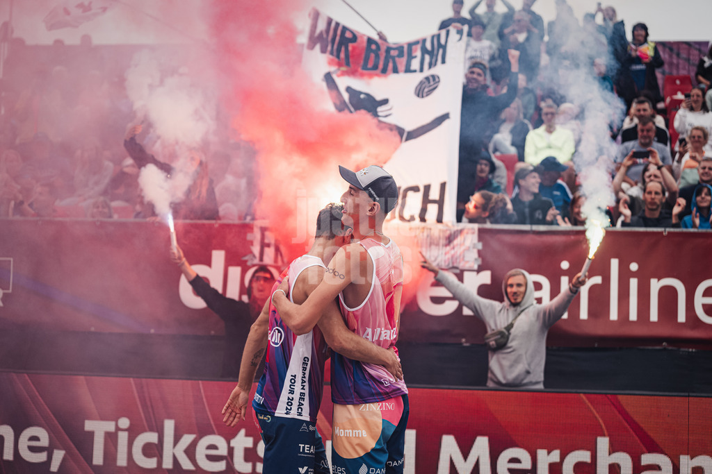 Beachvolleyball | Männer | Allianz German Beach Tour 2024 | Tourstop Kühlungsborn 2 | 18.08.2024 | vorne Eric Stadie (links) und Momme Lorenz (rechts) hinten Pyrotechnik von der 'Fraktion Bräune'