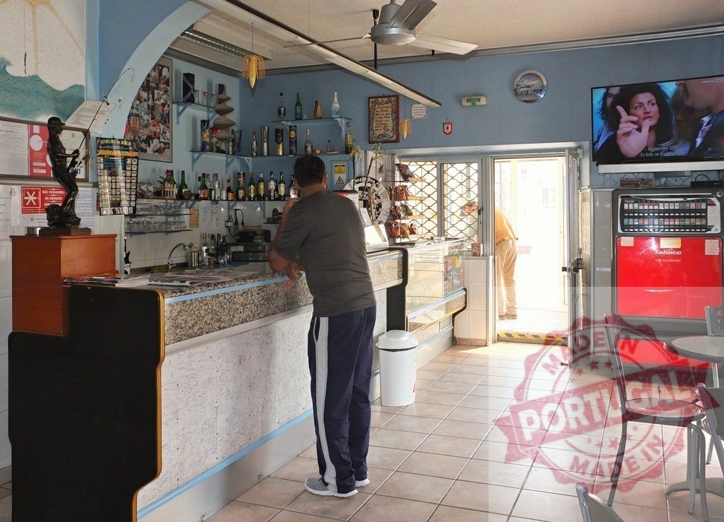 Man waiting at a bar counter inside a cafe | Man leaning on a bar watching television in an everyday life scene - Realized with Pictrs.com