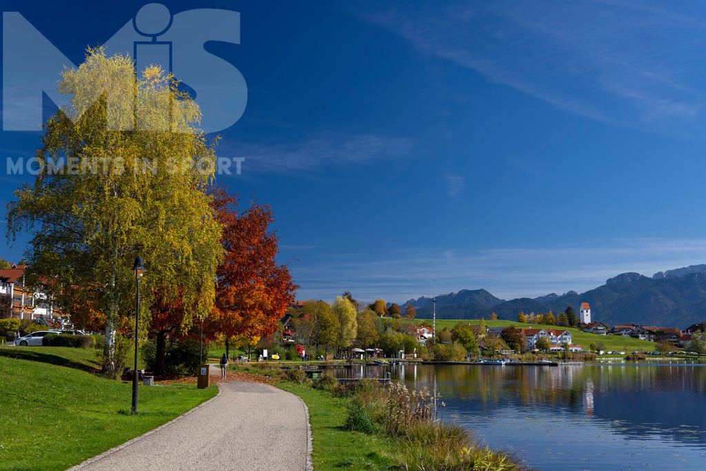 2.Liga-1860-HEIM.jpg | 17.10.2022, Herbst am Hopfensee im Allgäu (Bayern) bei Füssen. Bei sommerlichen Temperaturen geniessen viele Ausflügler die herbstliche Landschaft am See. Hier die Promenade in Hopfen am See. - Realisiert mit Pictrs.com