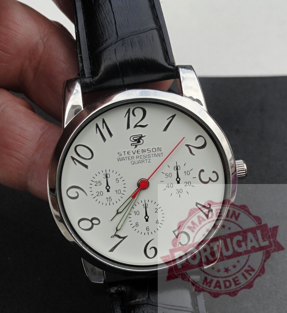 STEVENSON quartz wristwatch showing sub-dials and black strap | Hand holding a STEVENSON quartz wristwatch with white face and black strap - Realisiert mit Pictrs.com