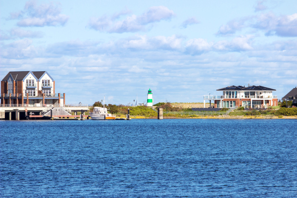 Wandbild: Ferienwohnungen Olpenitz | Dieses Wandbild im Querformat zeigt Ferienwohnungen in Olpenitz – im Hintergrund ist der Leuchtturm in Schleimünde zu sehen - Realisiert mit Pictrs.com