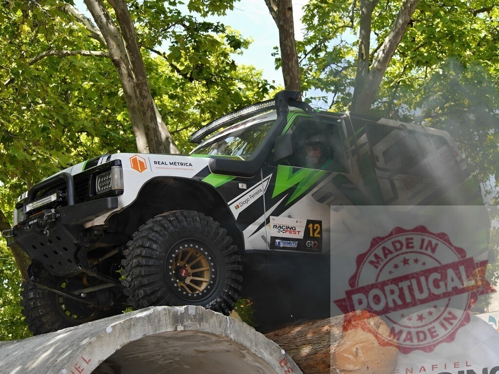 Offroad racing car climbing concrete pipe during competition | Offroad racing car climbing concrete pipe during a competition, creating a cloud of dust - Realisiert mit Pictrs.com