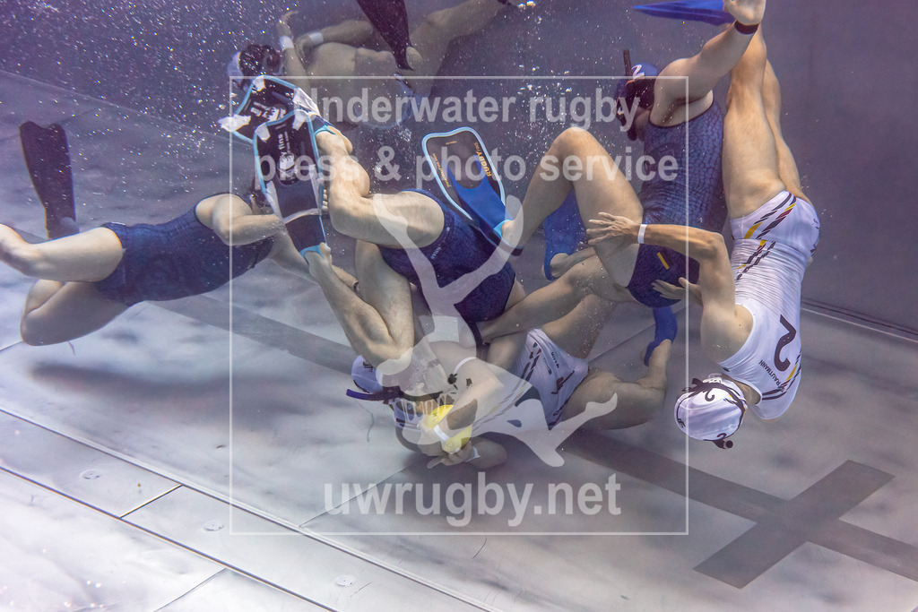 Deutsche Meisterschaft 2024 in Unterwasser-Rugby | Vorrundenspiel: Tauchclub Bamberg in weiß gegen DUC Krefeld in blau. Der Bamberger mit der Nummer 4 Lukas Tadda bringt den Ball vom eigenen Tor ins Mittelfeld. - Realisiert mit Pictrs.com