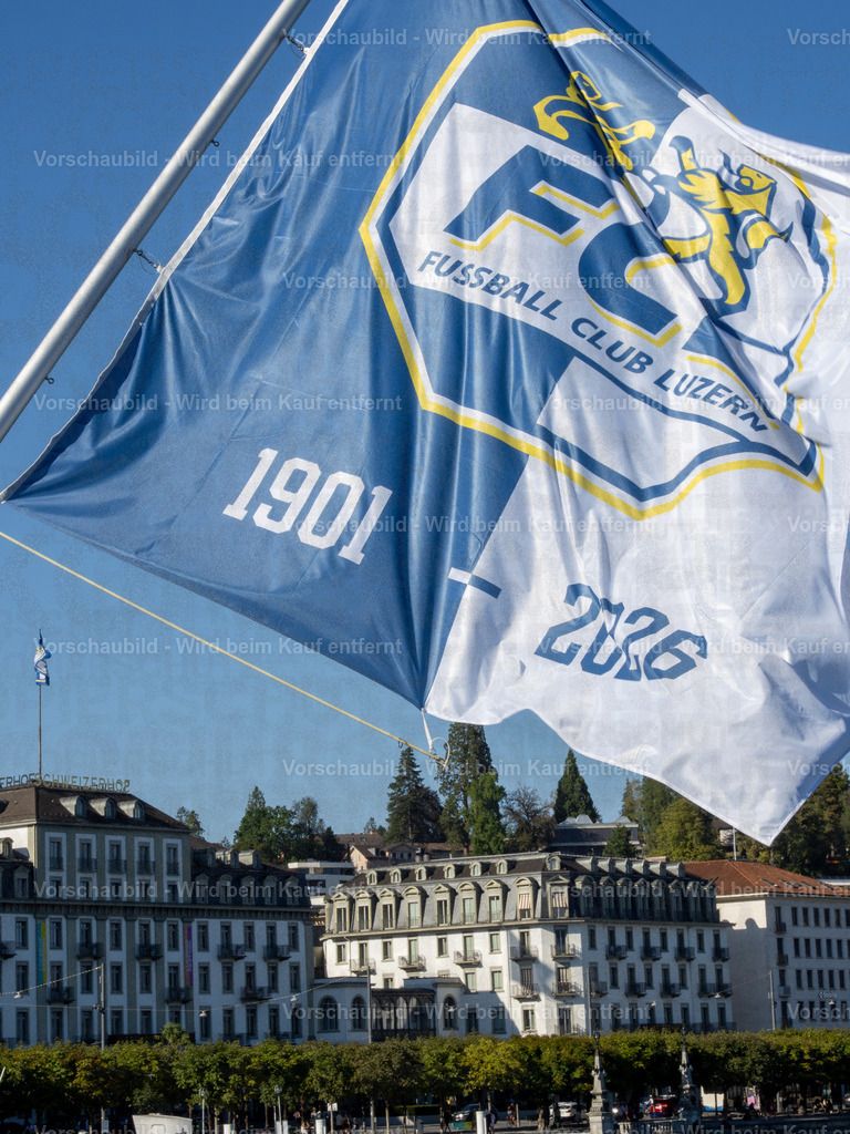 125 Jahre FCL – Luzern in Blau-Weiss | Die blau-weissen Fahnen wehen an der Seebrücke im Wind und zelebrieren das 125-Jahre-Jubiläum des FC Luzern. Dahinter erstreckt sich die Kulisse der Luzerner Seepromenade mit dem traditionsreichen Hotel Schweizerhof. - Realisiert mit Pictrs.com