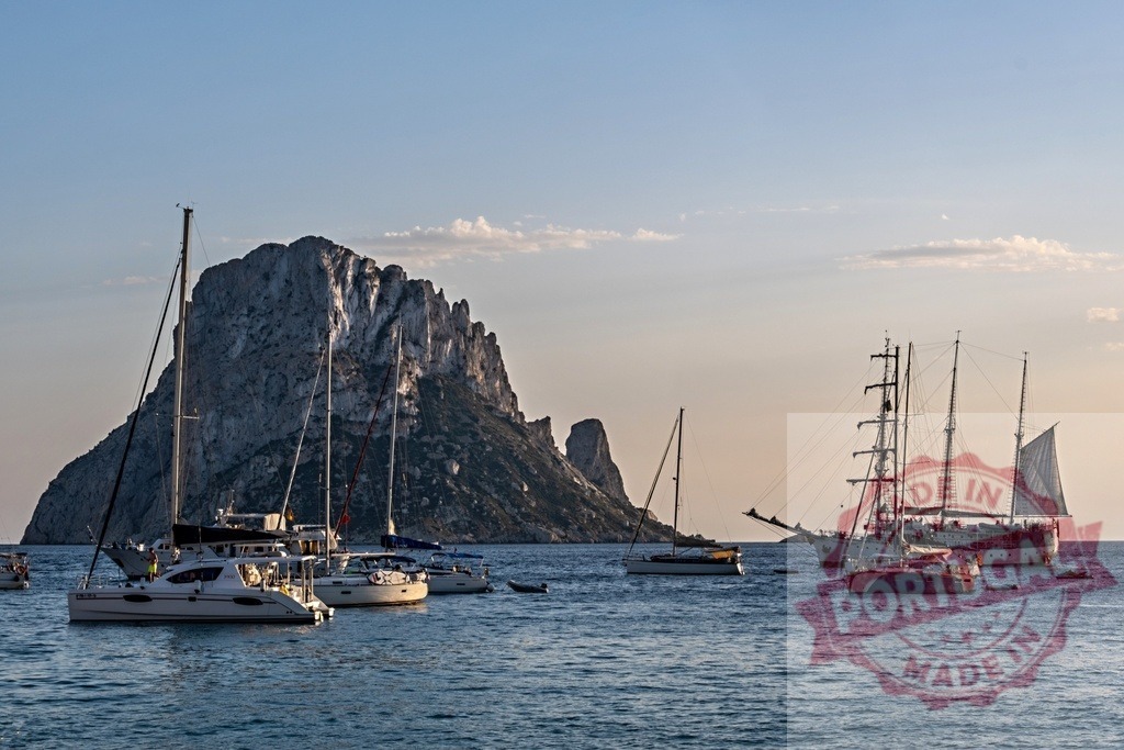 Es Vedrà island with yachts sailing Mediterranean sea at sunset | Yachts and sailboats moored near Es Vedrà rock island in the Mediterranean Sea during sunset - Realized with Pictrs.com