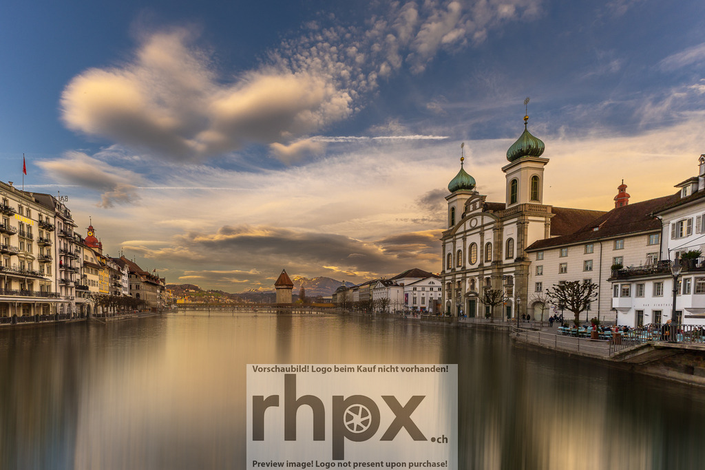 Jesuitenkirche und Kapellbrücke Luzern im Abendlicht | Barock. Weite. Flussidylle. Die prächtigen Türme der Jesuitenkirche thronen über der spiegelglatten Reuss, während die Kapellbrücke in der Ferne den Rahmen bildet. Ein Moment der absoluten Stille, in dem Architektur und Wolkenspiel in perfekter Harmonie verschmelzen. Wähle unter "Produktauswahl" dein Wunschformat: Vom klassischen Wandbild über Puzzle &amp; Tassen bis zum digitalen Download (z.B. als Handy-Hintergrund). - Realisiert mit Pictrs.com