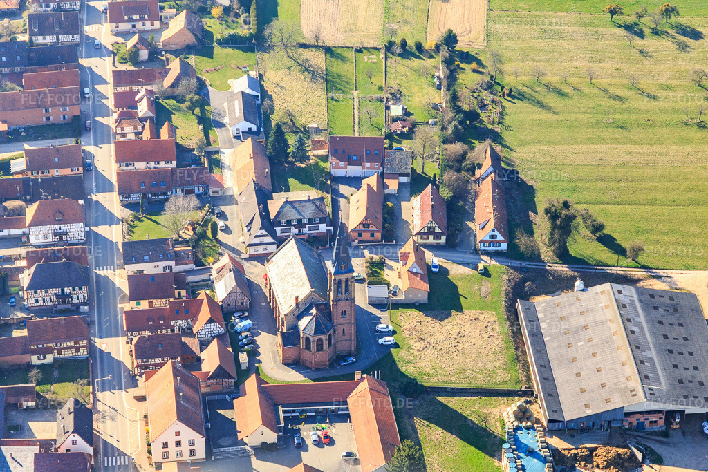 Luftbild: Kirchengebäude von Eglise Saint Jean im Dorfkern in Betschdorf im Bundesland Bas-Rhin in Frankreich. – Foto: IMG_097447.jpg vom 16.03.2017 durch Werner Riehm/FLY-FOTO.de – Auflösung des Originals: 5225 x 3483 px