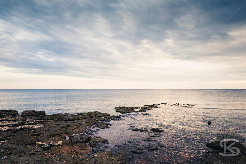 Dramatische Meereslandschaft bei Sonnenaufgang, bedeckter Himmel | Tauchen Sie ein in die dramatische und fesselnde Schönheit dieser Meereslandschaft. Der Kontrast zwischen den dunklen Gewitterwolken und dem hellen Sonnenlicht, das auf die Wasseroberfläche fällt, schafft eine intensive Atmosphäre und ein faszinierendes Lichtspiel am Horizont. - Realisiert mit Pictrs.com