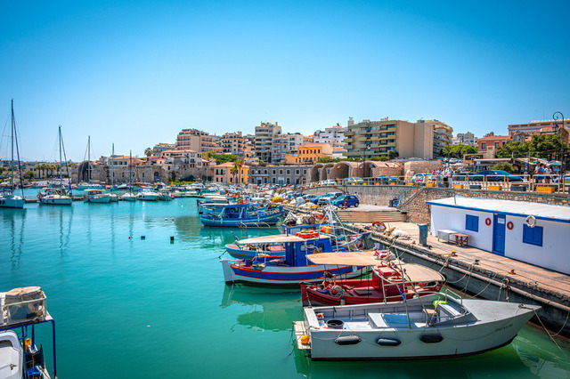 2026-07-20_11-06-59_770 | Hafen mit bunten Booten, angrenzenden Gebäuden und blauem Himmel in einer Küstenstadt, Heraklion, Kreta, Griechenland - Realisiert mit Pictrs.com