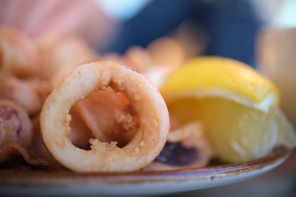 Panierte Tintenfischringe mit Zitrone | Barcelona, Spanien - May 02, 2024: Panierte Tintenfischringe mit Zitrone auf einem Teller. - Realisiert mit Pictrs.com