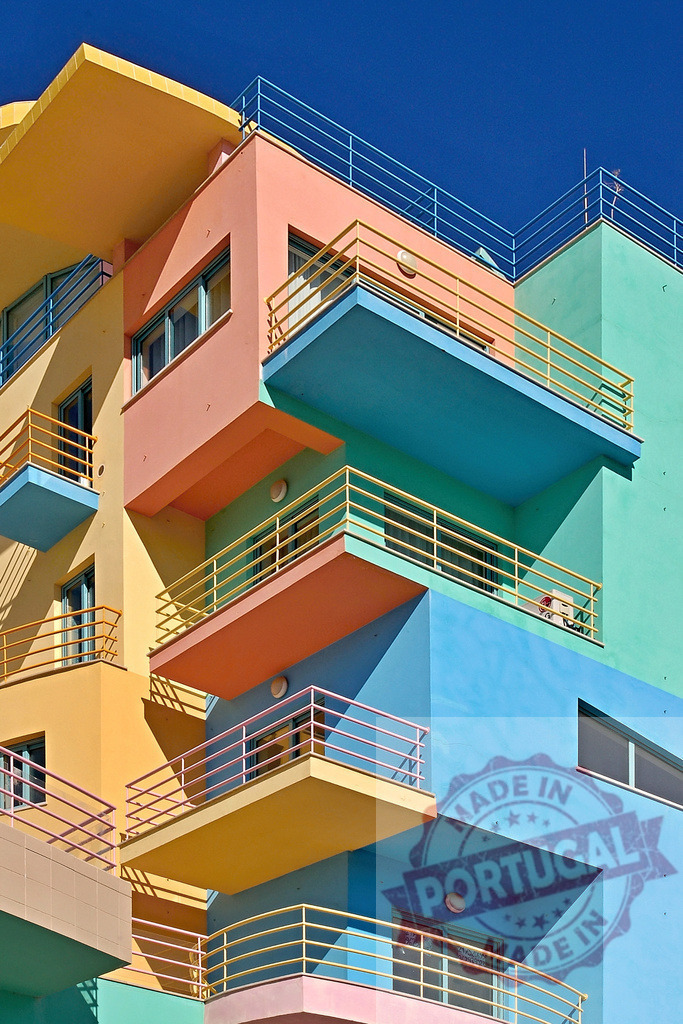 Colorful modern building with geometric balconies against blue sky | Modern building displaying vibrant colors and geometric architectural forms under a clear blue sky - Realisiert mit Pictrs.com