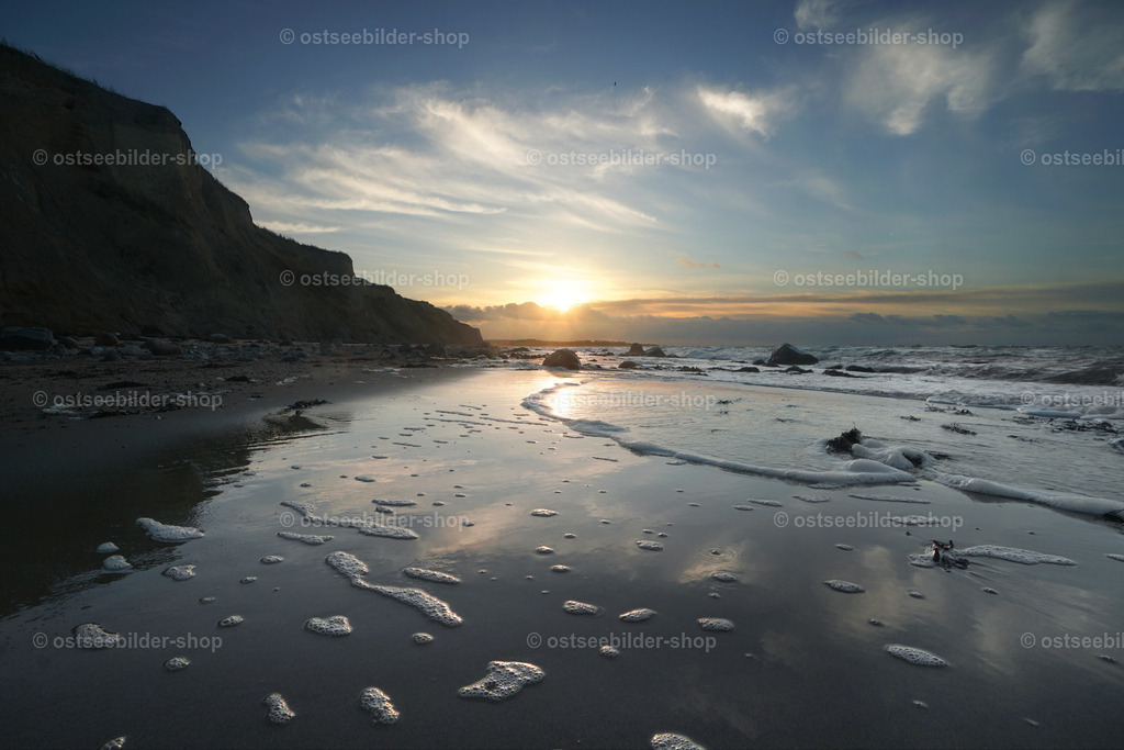 Steilküste mit auslaufender Brandung im Gegenlicht | Wie zerbrechliches Spiegelglas schiebt sich eine auslaufende Welle im Gegenlicht über den nassen Sand.