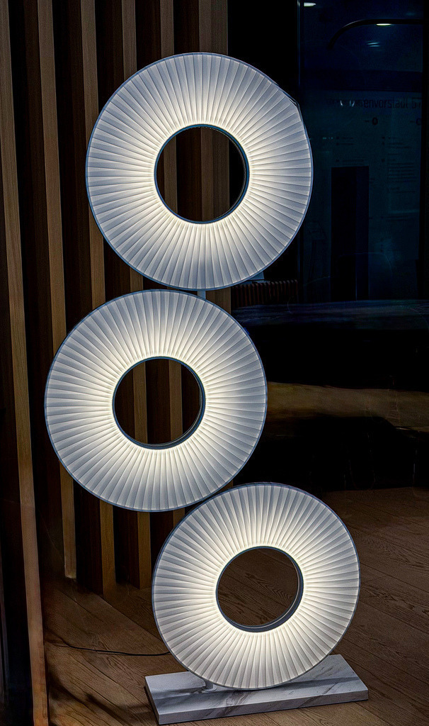 Wandbild Urban Geometry - Kreisförmige Architektur-Reflexion | Dieses exklusive Kunst-Wandbild fasziniert durch seine progressive, geometrische Ästhetik und ein hypnotisches Zusammenspiel aus Licht und Form. Die perfekt zentrierten, leuchtenden Kreisringe brechen die kühle Materialität der urbanen Architektur auf eine zutiefst kunstvolle Weise auf. Fotograf Robert Steinke fängt diese außergewöhnliche Komposition aus Symmetrie, Rhythmus und haptischer Oberflächenstruktur in gestochen scharfer Premium-Qualität ein. Ein absolutes High-End-Statement für moderne Wohnzimmer, urbane Lofts oder repräsentative Büroräume, die eine minimalistische und zugleich kraftvolle Dynamik ausstrahlen sollen. Perfekt geeignet als großformatiger Premium-Kunstdruck auf edlem Alu-Dibond, Leinwand oder unter brillantem Acrylglas für maximale Tiefenwirkung. - Realisiert mit Pictrs.com