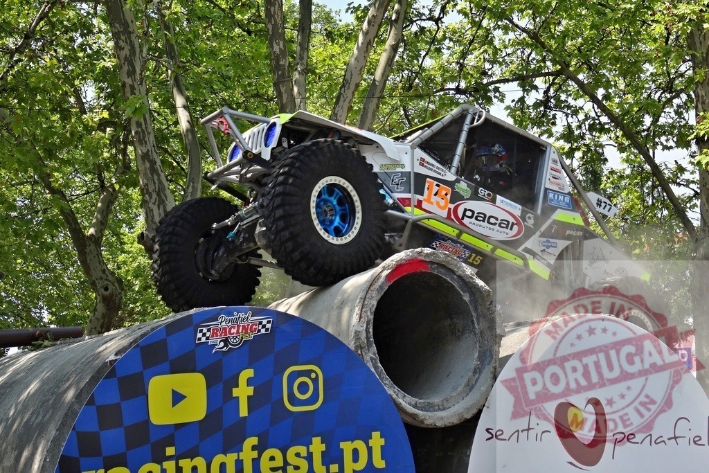 Jeep climbing concrete pipes during an off-road competition | Off-road vehicle driving over concrete pipes during a race competition - Realized with Pictrs.com