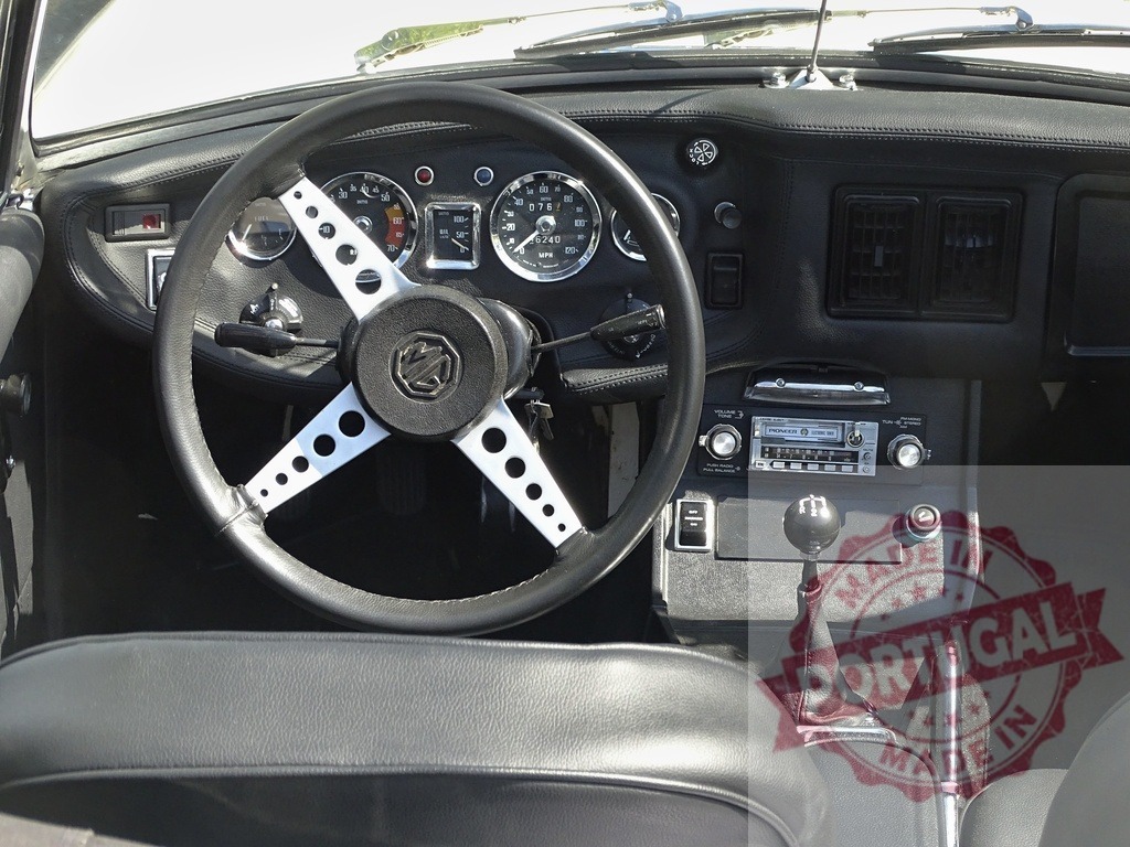 MG B roadster vintage car dashboard interior view | MG B classic car interior featuring steering wheel, dashboard, gauges, and gear shift - Realized with Pictrs.com