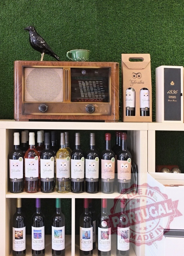 Wine bottles and vintage radio on rustic shelf | Assortment of Tyto Alba and Cortem wine bottles displayed on a wooden shelf with retro radio - Realisiert mit Pictrs.com