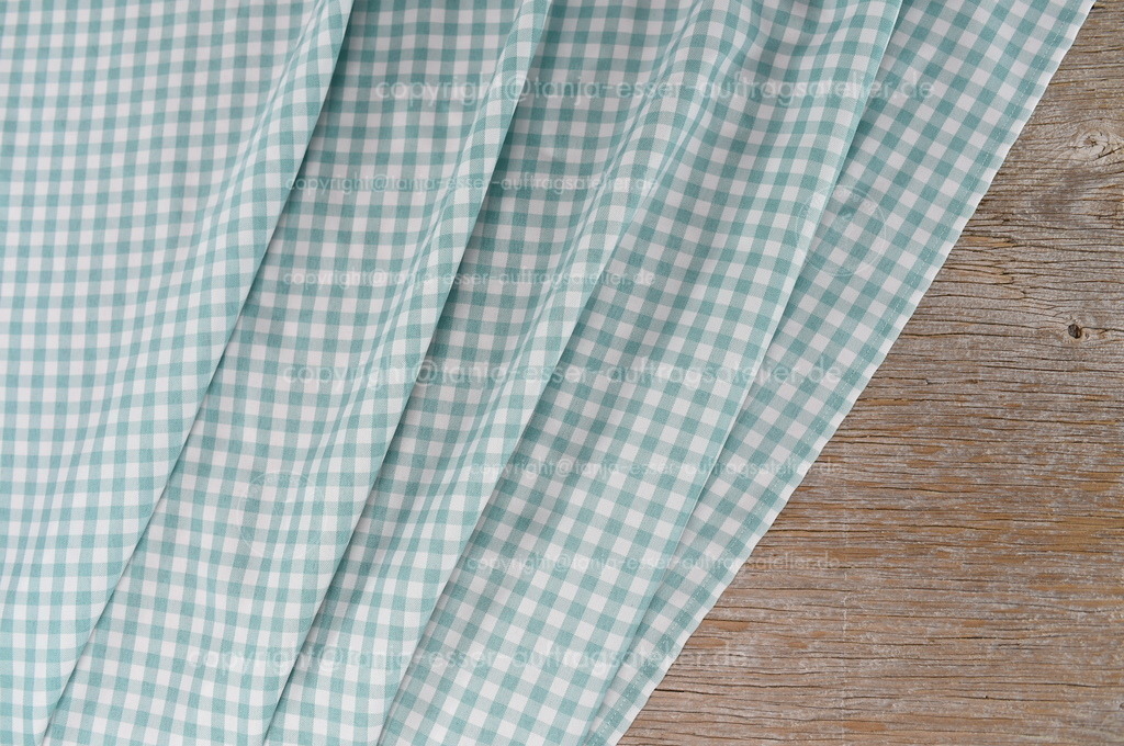 Hintergrund aus verwittertem Holz und türkis weiß karierten Stoff | Weiß und Mint karierte Stocfftischdecke liegt in Falten auf altem Holz als frischer Hintergrund. 