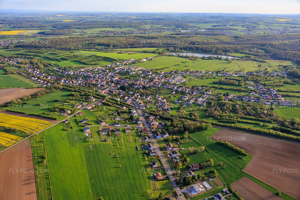 Aerial view: View of the town in front of the pond at Weihergraben from the north in Farschviller in the state Moselle, France. – Photo: IMG_154245.jpg taken on 04/17/2026 by Werner Riehm/FLY-FOTO.com – Resolution of the original: 6000 x 4000 px