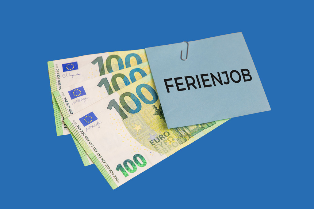 Ferienjob Symbolbild: Eurobanknoten und ein Zettel mit der Aufschrift FERIENJOB freigestellt vor blauem Hintergrund  | Ferienjob Symbolbild: Eurobanknoten und ein Zettel mit der Aufschrift FERIENJOB freigestellt vor blauem Hintergrund  - Realisiert mit Pictrs.com