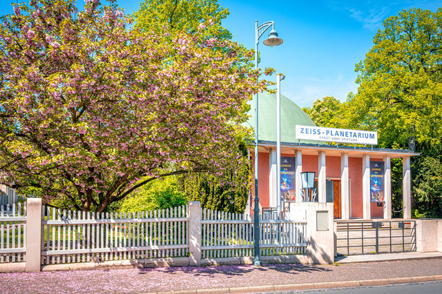 2025-05-01_11-48-28_140 | Ein Planetarium umgeben von blühenden Bäumen mit rosa Blüten an einem sonnigen Tag, Jena, Thüringen, Deutschland - Realisiert mit Pictrs.com