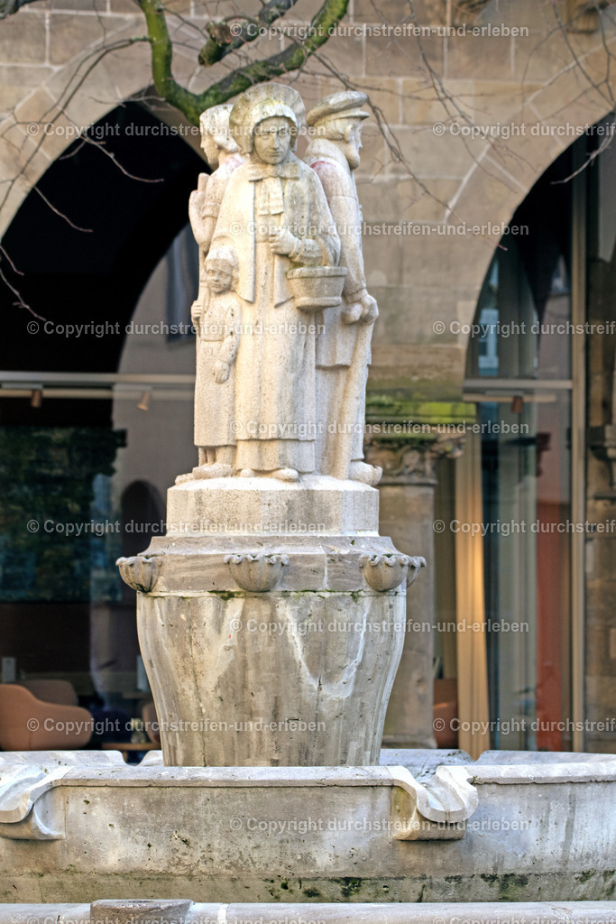  Lambertibrunnen vom Prinzipalmarkt in Münster aus gesehen | Der Lambertibrunnen weist durch die Darstellung einer bäuerlichen Familie auf die Tradition des Tanzens zu Ehren des Heiligen Lambertus hin. - Realisiert mit Pictrs.com