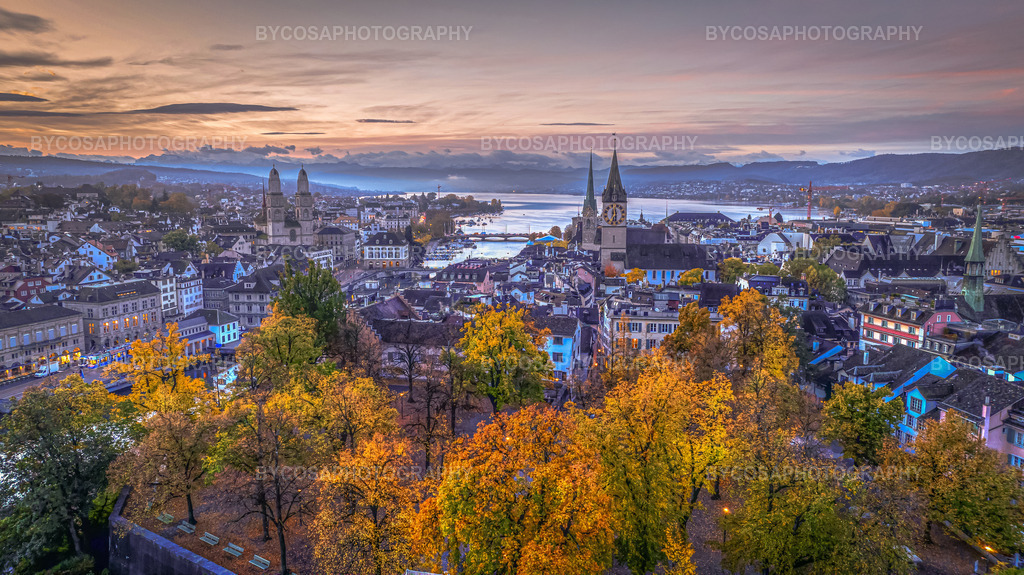 Autumn Over Zürich _ Lindenhof Sunrise | Eine atemberaubende Luftaufnahme von Zürich im Hochherbst. Der Lindenhof erstrahlt in goldenen und orangen Farbtönen, während sich die Altstadt in sanftem Pastelllicht zum See hin öffnet. Grossmünster, Fraumünster und St. Peter thronen wie Wächter über der Stadt, während der Himmel von Violett in warme Morgen- und Abendfarben wechselt.Dieser FineArt-Druck bringt die Wärme, die Nostalgie und den Zauber des Herbstes in jeden Raum – perfekt für alle, die Zürich, die Natur und stimmungsvolle Landschaften lieben. - Realisiert mit Pictrs.com