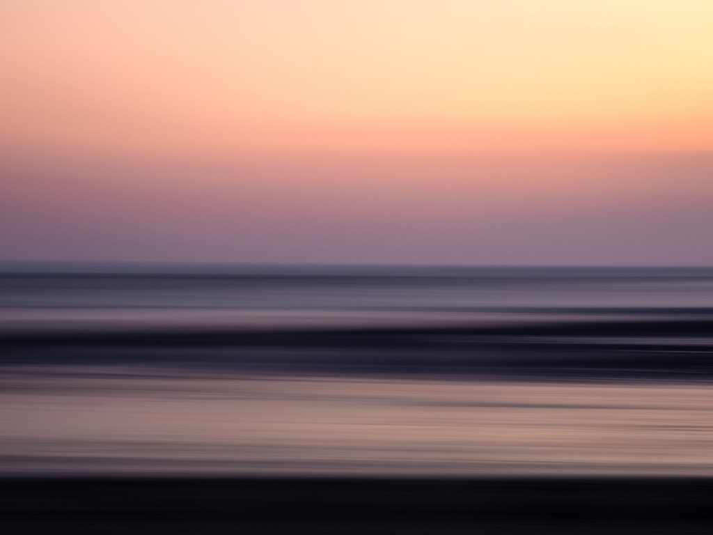 Die Schwelle | In der Dämmerung der Bucht von Le Mont-Saint-Michel verschmilzt das Licht mit der Zeit. Weiche Verläufe von Gold, Violett und Dämmerblau überziehen das ruhige Wasser, als hätte der Horizont selbst den Atem angehalten. Die Gezeiten, die das Land täglich neu zeichnen, ruhen für einen Moment – als wollten auch sie lauschen. Das Bild ist wie ein Traum, der sich gerade erst zu formen beginnt. Nichts ist scharf, alles ist Bewegung und Stille zugleich. Dieses Bild fängt die Schwelle ein, zwischen dem Hier und Jetzt, dem was war und dem was sein wird. Es ist ein Blick in die Tiefe der Elemente – und in die Tiefe des eigenen Inneren. - Powered by Pictrs.com