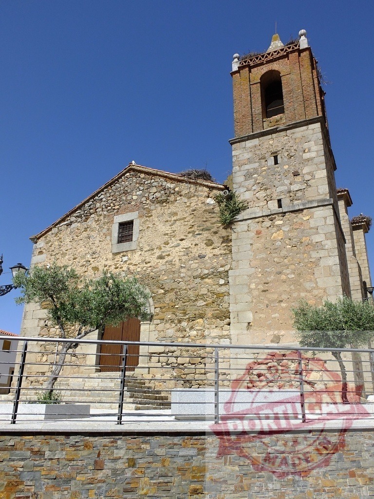 Old stone church with brick bell tower and stork nests. Spain - Extremadura | Old stone church featuring a brick bell tower and multiple stork nests under a clear blue sky - Realized with Pictrs.com