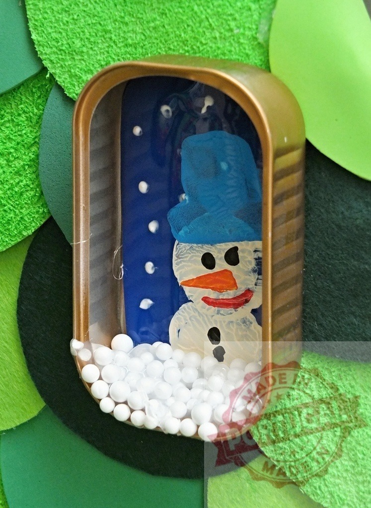 Snowman painting inside sardine can during christmas time | Handmade christmas decoration representing a snowman painting inside a sardine can with polystyrene balls resembling snow - Realized with Pictrs.com