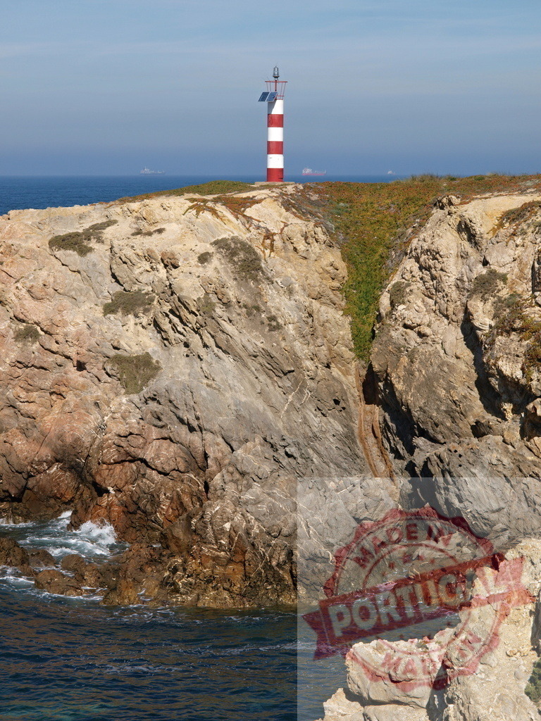 Red and white lighthouse on a rocky cliff overlooking ocean | Lighthouse standing on a rugged cliff, guiding navigation with ocean and blue sky background - Realized with Pictrs.com