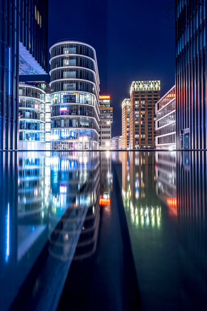 Reflected Geometry | In Düsseldorf’s Medienhafen, light and architecture merge into a perfect symmetry. Glass and steel reflect upon still water, creating a futuristic dreamscape — calm, precise, and full of quiet rhythm. - Realisiert mit Pictrs.com