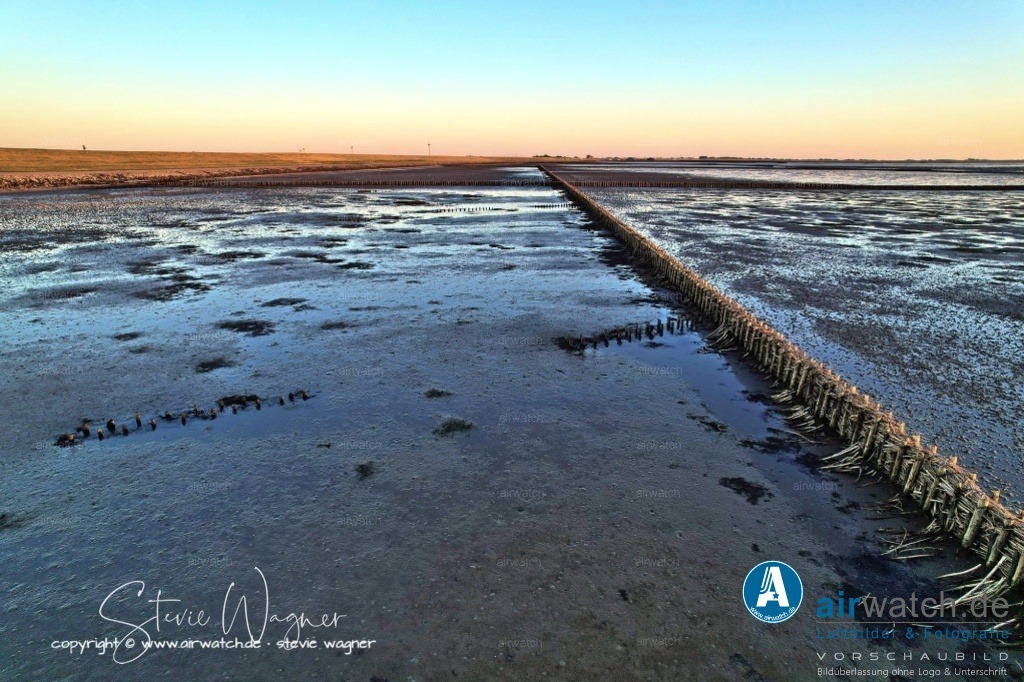 Nordsee, Nordfriesland, Beltringharderkoog, Luettmoorsee, Holmer Siel, Landgewinnung | Landgewinnung & Küstenschutz in Nordfriesland - Um die Aufschlickung zu beschleunigen, werden sogenannte Lahnungsfelder angelegt. Diese sind doppelte Reihen von Holzpfählen, die in den Wattboden gerammt werden. Zwischen die Pfähle werden Zweige und Reisigbündel gepackt. Diese Lahnungsfelder teilen das Watt in rechteckige Felder, in denen das auflaufende Wasser schneller zur Ruhe kommt. Dadurch können die Schwebeteilchen, die das Meer mitbringt, besser absetzen und neue Landflächen entstehen.