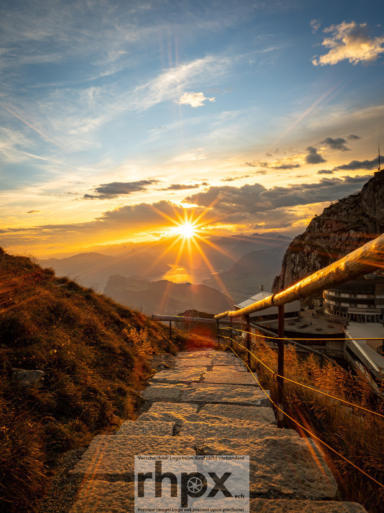 Pilatus Sonnenaufgang mit Blick auf den Vierwaldstättersee | Der Aufstieg zum Pilatus im Morgenlicht zeigt die Sonne über den Alpen. Der beleuchtete Weg und die klare Sicht bis zum Vierwaldstättersee zeigen die typische Landschaft der Zentralschweiz.  - Realisiert mit Pictrs.com