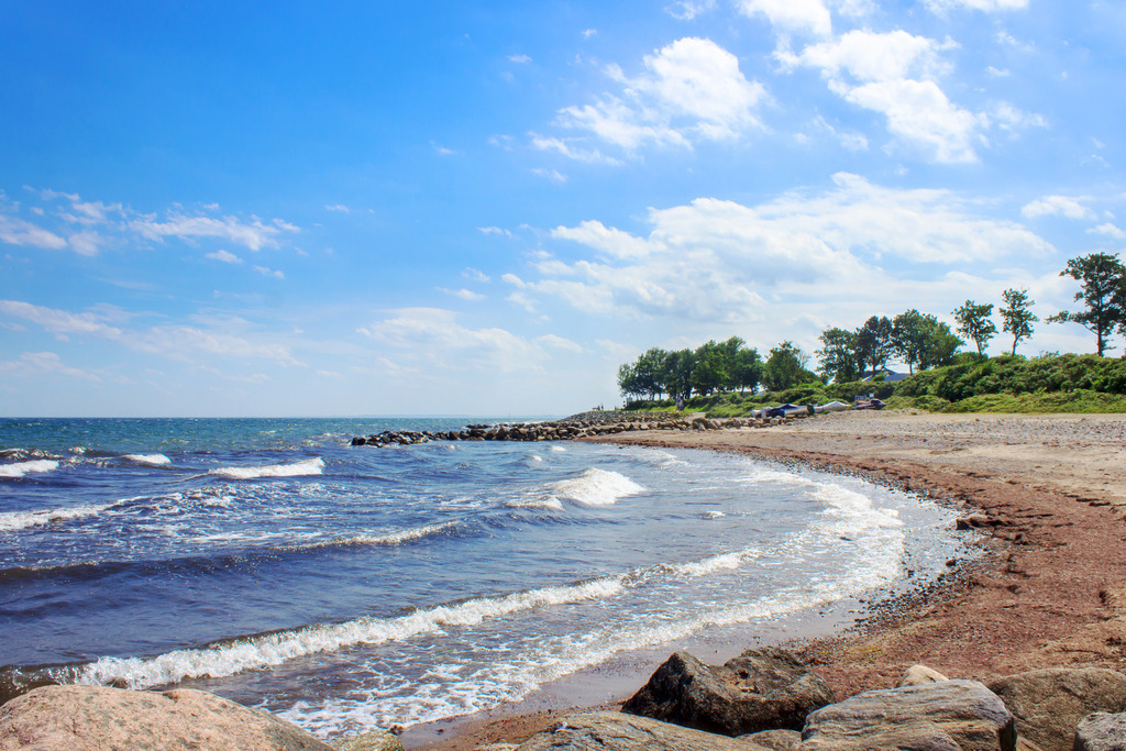 Wandbild: Ruhe am Meer – Küstenlandschaft mit sanften Wellen | Ein idyllischer Blick auf den Sandstrand von Schönhagen, wo sanfte Wellen auf das Ufer treffen und die Küstenlinie sich malerisch entlangzieht. Die natürliche Schönheit des Strandes mit seinen verstreuten Felsen und der ruhigen Atmosphäre lädt zum Verweilen und Träumen ein. Umgeben von grünen Bäumen und einer friedlichen Küstenlandschaft vermittelt dieses Wandbild das Gefühl von Ruhe und Weite – perfekt, um das maritime Lebensgefühl direkt ins Zuhause zu holen. - Realisiert mit Pictrs.com
