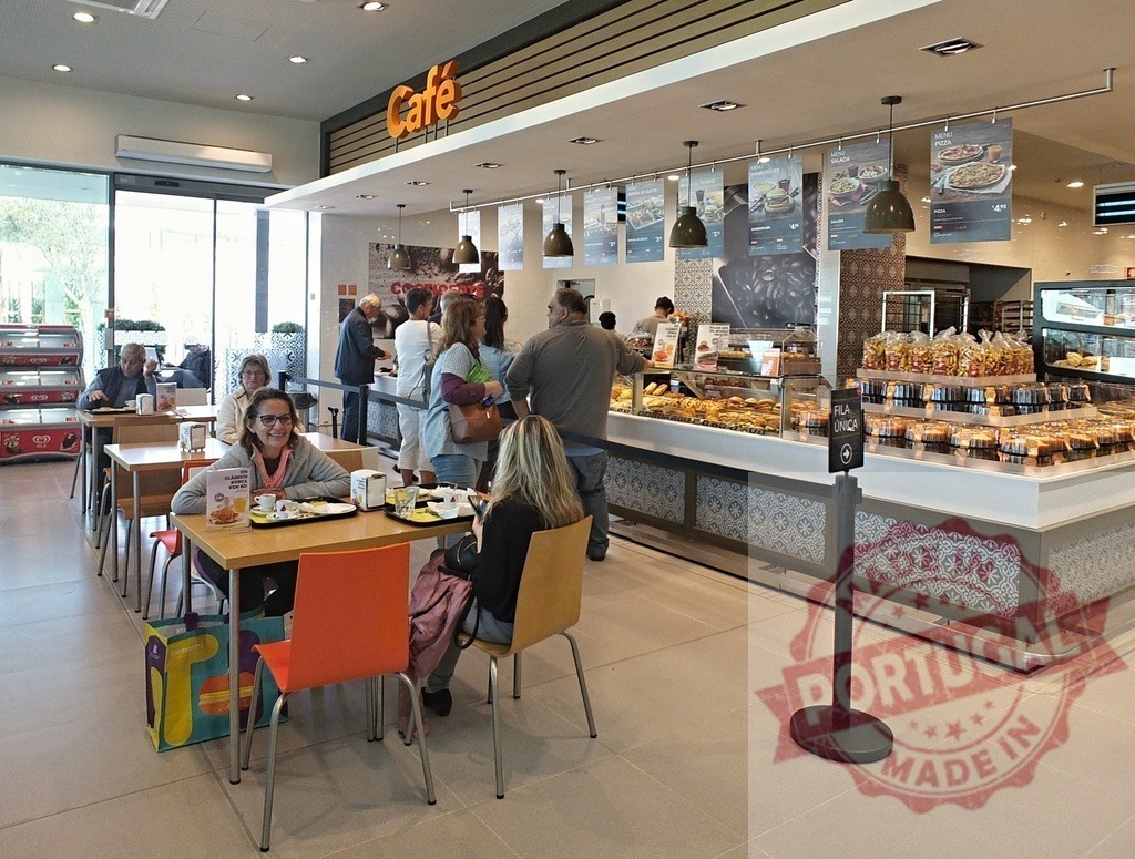 Customers enjoying pastries and coffee at modern cafeteria | People socialising while eating and ordering food at a busy cafe - Realisiert mit Pictrs.com