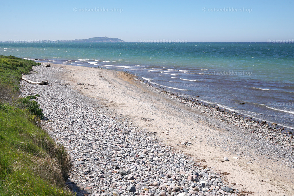 Steiniger Strand mit Blick nach Hiddensee | Das Bild zeigt einen Steinestrand auf Rügen mit weitem Blick über die Ostsee bis zur Insel Hiddensee am Horizont.