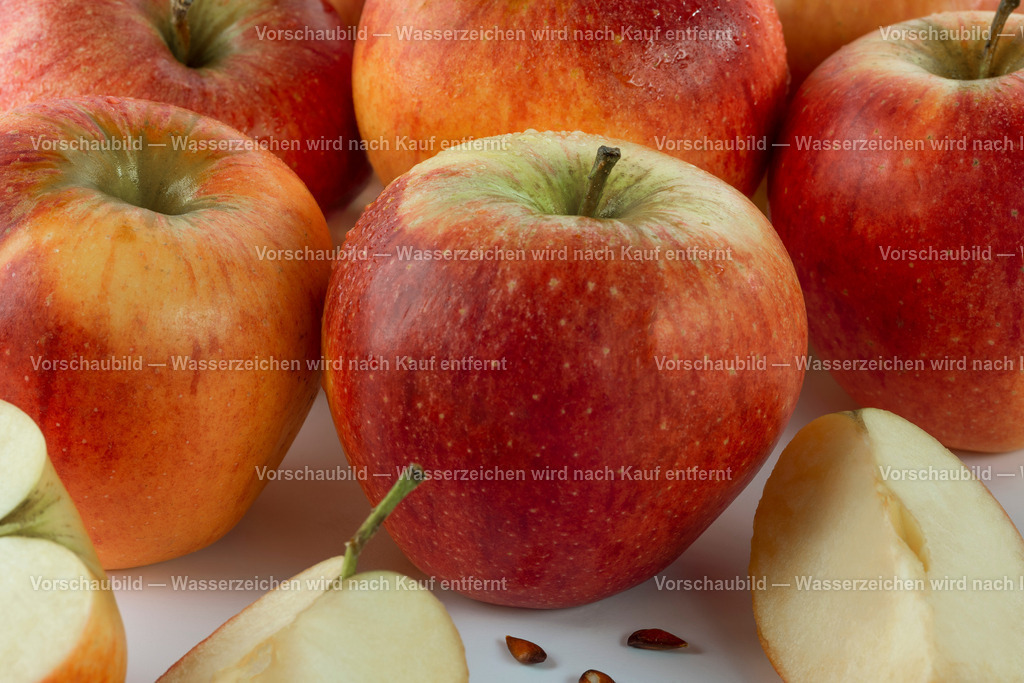 Nahaufnahme von mehreren frische, rote Äfeln | Nahaufnahme von mehreren frische, rote Äfeln. Im Vordergrund ein aufgeschnittener Apfel mit Kernen. - Realisiert mit Pictrs.com