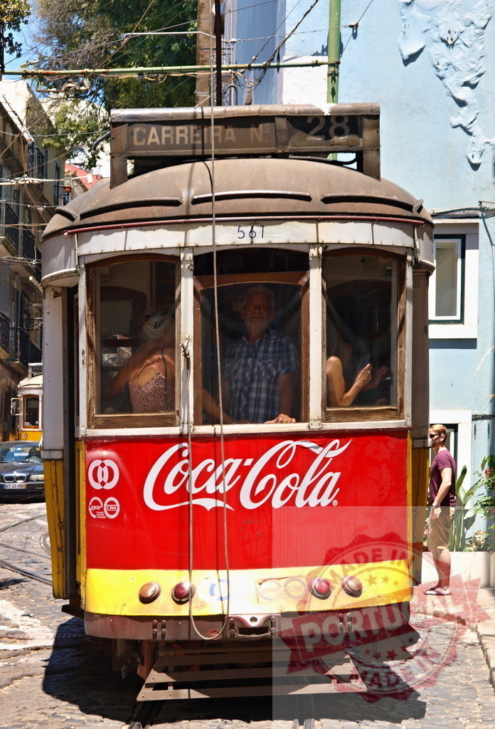 Tourists riding vintage Lisbon tram number 28 with Coca-Cola advertisement | Passengers enjoying a ride on a historic tram in Lisbon, Portugal, featuring a prominent Coca-Cola advertisement - Realized with Pictrs.com