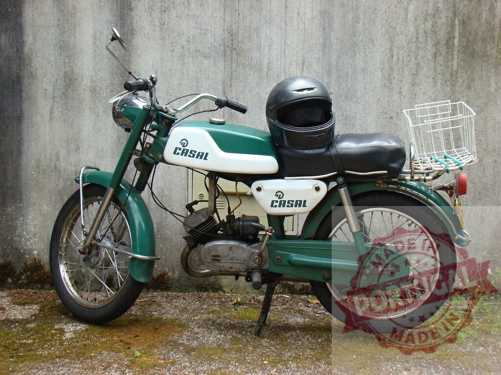 Vintage casal moped parked against weathered wall with helmet and basket | Green and white vintage Casal moped with helmet and basket parked against a weathered wall, evoking a sense of nostalgia and classic style - Realized with Pictrs.com