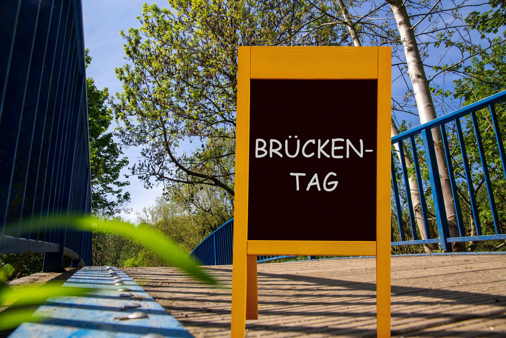 Brückentag Bild mit Brücke  | (Fotomontage) Brücke im Wald und ein Aufsteller mit der Aufschrift BRÜCKENTAG  - Realisiert mit Pictrs.com