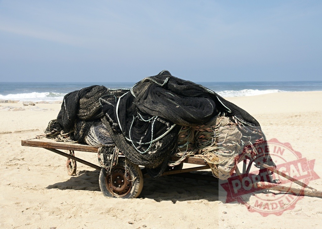Aveiro Region - Portugal Fishing nets on old cart sitting on sandy beach | Fishing nets and ropes piled on a rusty cart on a sunny beach with the ocean in the background - Realisiert mit Pictrs.com