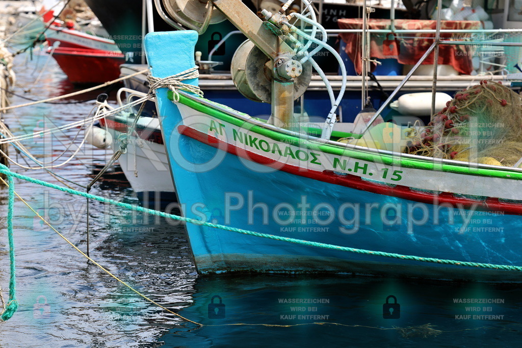 Blaues Boot im Hafen – Farbe, Form und maritime Stimmung | Das Bild zeigt den Bug eines hellblauen Fischerboots, das im Hafen vertäut ist. Die Bordwand ist mit einem grün-roten Streifen verziert, und ein Tau ist um den Bug gewickelt. Im Hintergrund sind weitere Boote, Fischernetze und das ruhige Wasser des Hafens zu sehen. Die Aufnahme wirkt lebendig und farbenfroh, typisch für einen mediterranen Fischerhafen.Was das Bild besonders macht:Es fängt die Authentizität des Alltagslebens am Meer ein – die Spuren der Arbeit (rostige Mechanik, abgenutzte Netze, Tauwerk) stehen im Kontrast zur leuchtenden Farbgebung des Bootes. Die Komposition mit dem diagonalen Bug, den sich kreuzenden Tauen und dem Spiegelbild im Wasser erzeugt eine dynamische, fast malerische Wirkung. Die Farbgebung ist kräftig, aber nicht überladen – sie wirkt natürlich und einladend.Dieses Bild ist bei nikograph.eu erhältlich und kann als verschiedene Fotoprodukte bestellt werden – etwa als gerahmter Druck, Leinwandbild, Poster oder als Wanddekoration in verschiedenen Größen und Materialien.