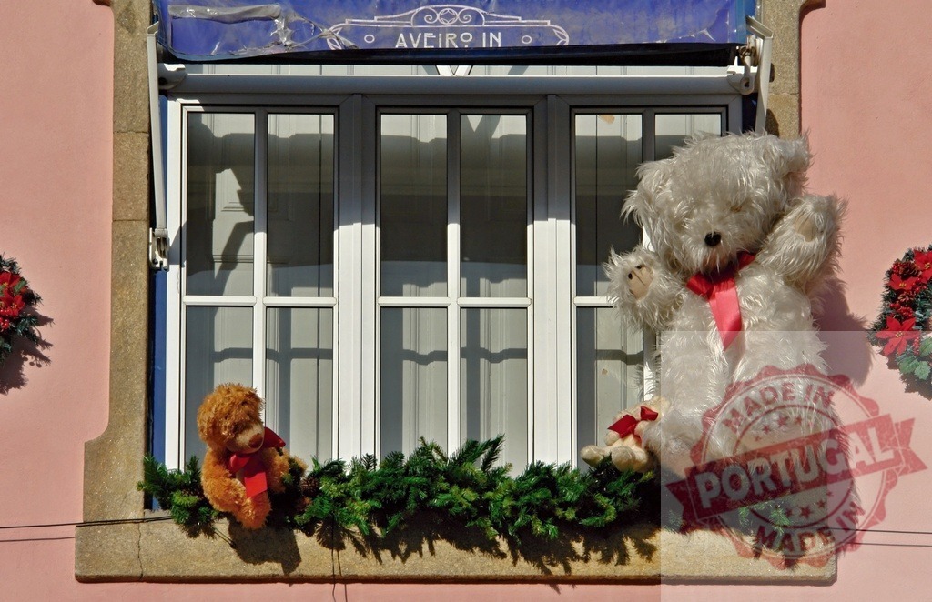 Teddy bears decorating window sill with Christmas garland in Aveiro | Decorative teddy bears on an exterior building window sill with Christmas garland and poinsettias - Realisiert mit Pictrs.com