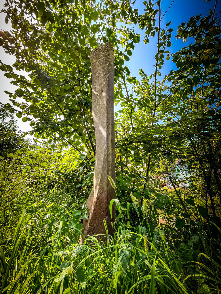 Stele - Hirzenhain | Eine Basalt-Stele versteckt sich am Rand des Vulkanradweges.Kleine Akzente können große Wirkung entfalten. Zurzeit muss man im öffentlichen Raum noch nach Kunstwerken und angelegten Grünanlagen suchen. Doch manchmal braucht es nur einen zentralen Farbfleck, um den Wandel anzustoßen. - Realisiert mit Pictrs.com