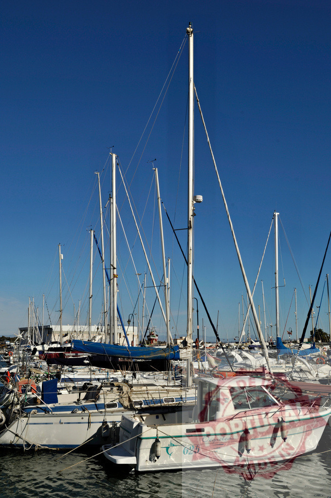 Marina crowded with sailboats and motorboats in harbor | Sailboats and motorboats moored in a bustling marina under a clear blue sky - Realisiert mit Pictrs.com