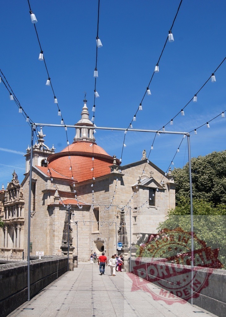 São Gonçalo Bridge Amarante Portugal urban travel scene | People walking on São Gonçalo Bridge with the church and festive string lights overhead - Realized with Pictrs.com