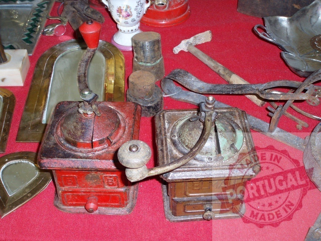 Two antique Elma coffee grinders at flea market | Two vintage coffee hand grinders showing wear and rust on a red background - Realized with Pictrs.com