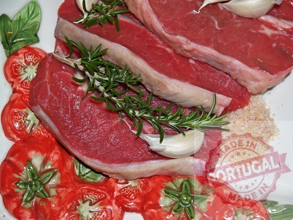Raw beef steaks with rosemary garlic and salt | Raw beef steaks with fresh rosemary, garlic cloves, and seasoning salt on a decorative plate - Realized with Pictrs.com